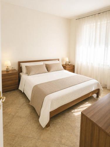 a white bedroom with a large bed and a window at Condominio Sole - Agenzia Cocal in Caorle