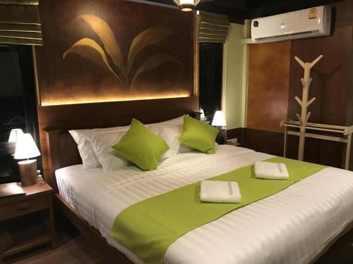 a bedroom with a large bed with green pillows at Lana Hotel in Chiang Mai