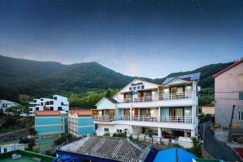 a view of a building with mountains in the background at Geoje Ocean Love Pension in Geoje