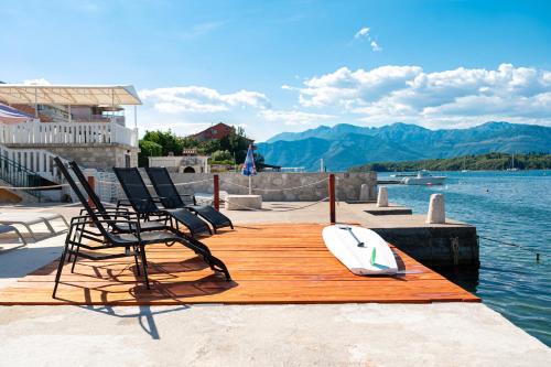 a wooden dock with chairs and a surfboard on it at Dubravcevic Residence in Tivat