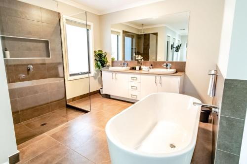 a bathroom with a tub and two sinks and a shower at Amaroo in Bright