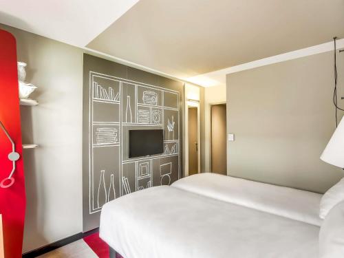 a room with a bed and a wall with a tv at ibis Paris Bercy Village in Paris