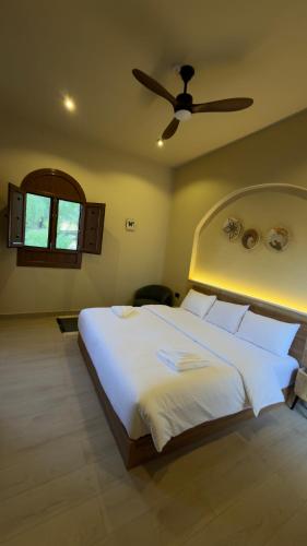 a bedroom with a large white bed with a ceiling fan at Betham Chalet in Nizwa