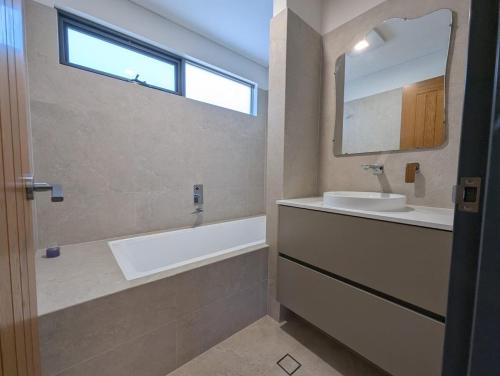 a bathroom with a tub and a sink and a mirror at The Mandurah Hideaway in Mandurah
