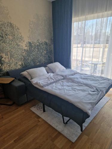 a bed in a room with a large window at Oja 69-4 Apartment in Pärnu