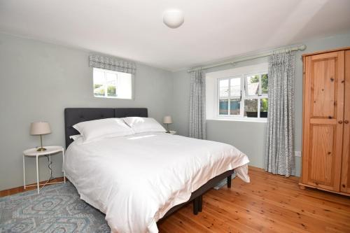 a bedroom with a large white bed and two windows at High Field Cottage Rosscarbery in Rosscarbery