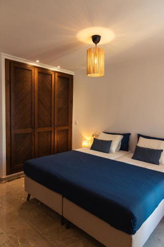 a bedroom with a bed with blue sheets and a chandelier at La Manga Amarilla in Cartagena