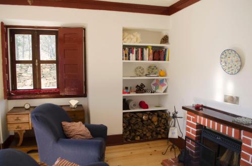 a living room with a fireplace and a chair at Casa Cerro da Correia in Manteigas
