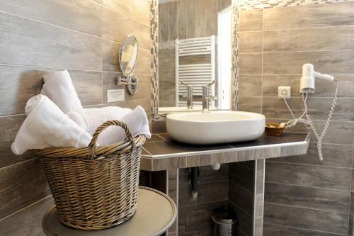 a bathroom with a sink and a basket at Hôtel La Grange Aux Marmottes in Viscos