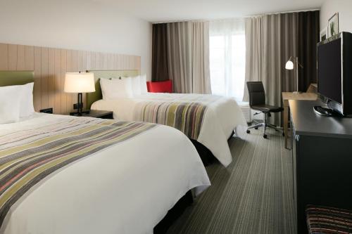 a hotel room with two beds and a desk at Country Inn & Suites by Radisson, Madison West, WI in Middleton