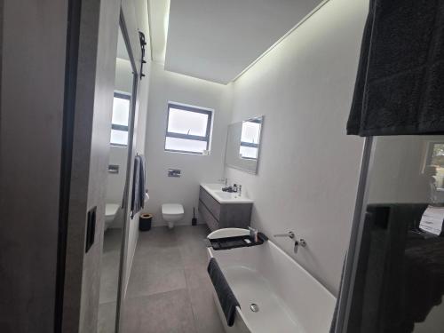a white bathroom with a tub and a sink at Terra Nova Suites and Spa in Gqeberha