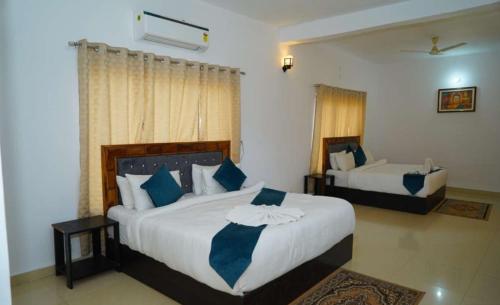 a bedroom with two beds with blue and white pillows at Blue River Resort in Rāmnagar