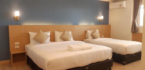 ein Schlafzimmer mit zwei Betten mit weißer Bettwäsche in der Unterkunft Ceniq Hotel in Sathani Nakhon Lampang