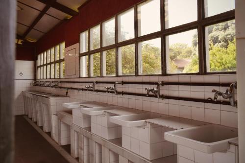 a row of sinks in a public restroom with windows at HolaCamp Luarca in Luarca