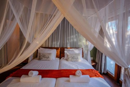a bedroom with two beds with white drapes at Spacious Family Villa, close to Krugerpark entrance in Phalaborwa