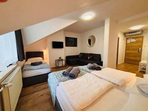 a bedroom with two beds and a couch at Hotel Pohorje in Maribor