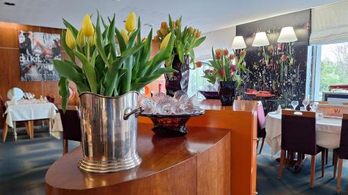 a vase of flowers on a table in a restaurant at Logis Hôtel Relais de Vincey in Vincey