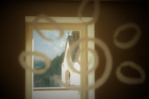a window view of a church with a windmill at Ciasa Alpina Relax Hotel in Moena