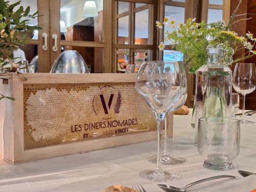 a table with wine glasses and a sign on it at Logis Hôtel Relais de Vincey in Vincey