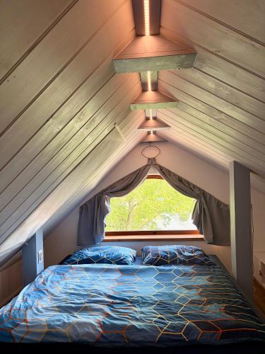 a bed in a tiny house with a window at Sunrise Tiny House Malešov in Malešov