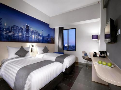 a hotel room with two beds and a desk at StarRay Hotel Jakarta Kebayoran in Jakarta