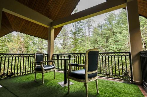 two chairs sitting on a porch with a railing at The Woodlane Cottage in Kūfrī