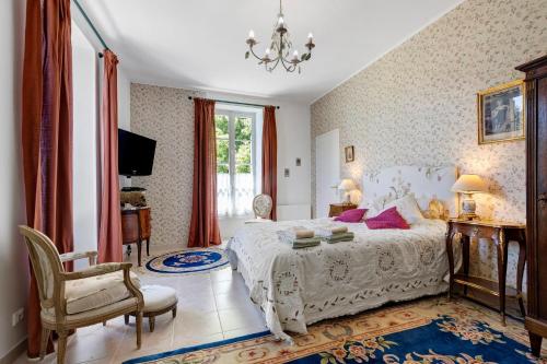 a bedroom with a white bed and a chair at La maison de Léandre - Medoc in Saint-Seurin-de-Cadourne