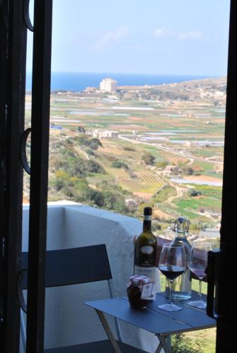 a table with two glasses and a bottle of wine at Secco's Seaview Accommodation in Mġarr