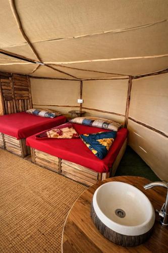 a room with two beds and a sink in a tent at Sholanest Mud House and Farm Stay in Vattavada Near Munnar in Vattavada