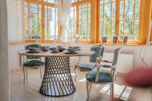 a table and chairs in a room with windows at Sunset Lovers Residence in Liepāja