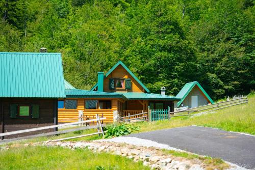 a wooden house with a green roof and a driveway at Katun Senic in Berane