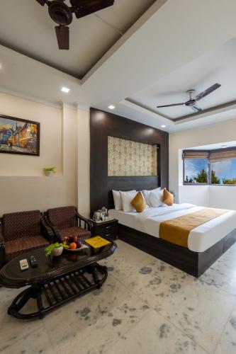 a bedroom with a bed and a couch and a table at Hotel Dharam Villa By Jai Guru Ji At Sector 11, Noida in Noida