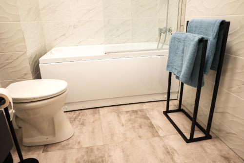 a bathroom with a toilet and a bath tub and a towel rack at AMA Residence Premium Apartment in Târgu-Mureş