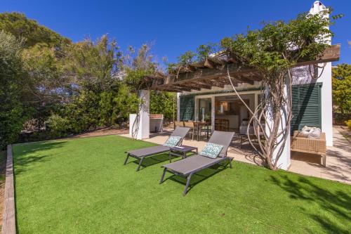 a lawn with two chairs and a pergola at Biniancolla Ginesta in Biniancolla
