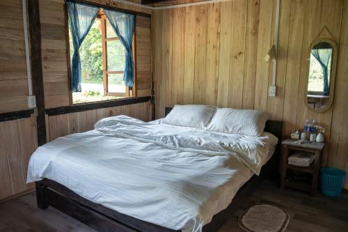 a bedroom with a bed in a wooden room at Nùng Indigo in Cao Bằng