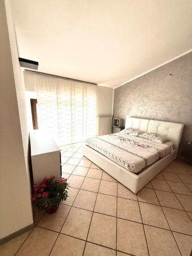 a bedroom with a white bed and a large window at Appartamento la rosa in Marone
