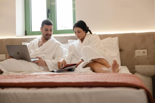 a man and woman sitting on a bed with a laptop at Aegora Residence in Kalithies