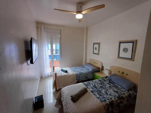 a bedroom with two beds and a ceiling fan at KAIROS HOME y Garaje , Algemesí Home in Algemesí