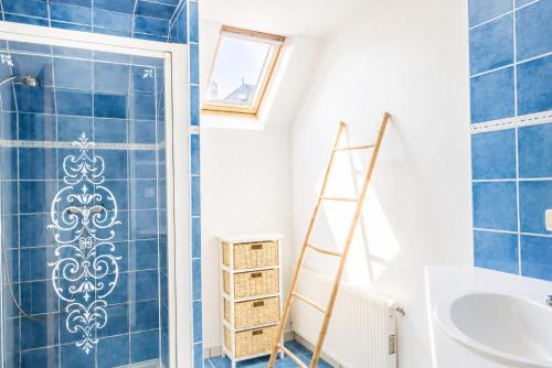 a bathroom with blue tiles and a ladder next to a shower at Cacatoès in Saint-Aignan