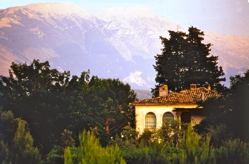 a house in a field with a mountain in the background at Agriturismo "Borgo Madonna degli Angeli" - charming cottages in the gardens ! in Tocco da Casauria