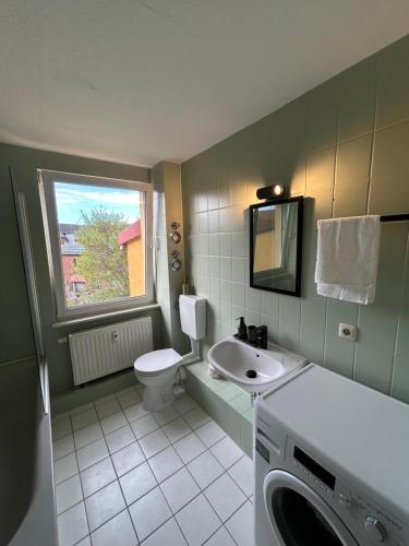 a bathroom with a sink and a toilet and a window at Stadtloft am Schillerpark in Dessau