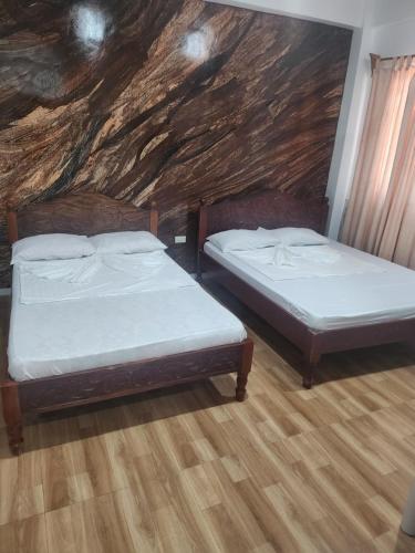 two beds in a room with a stone wall at Yasmin's Transient House in Pagudpud