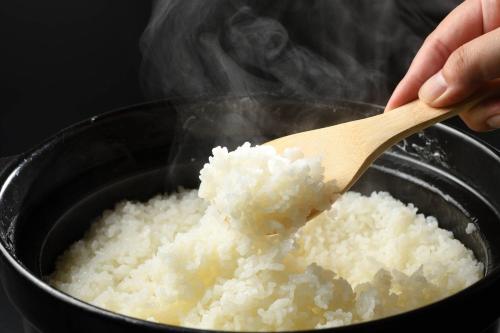 a person stirring a pot of rice with a wooden spoon at 六日町温泉 龍氣 in Minami Uonuma