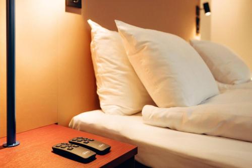 two remote controls sitting on a table next to a bed at Scandic Go, Kungsgatan 14 in Jönköping