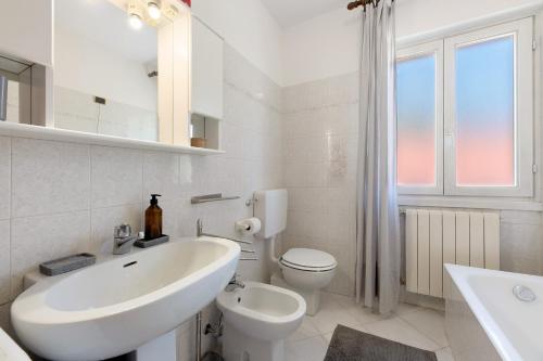 a white bathroom with a sink and a toilet at Casa Ezia in Porlezza