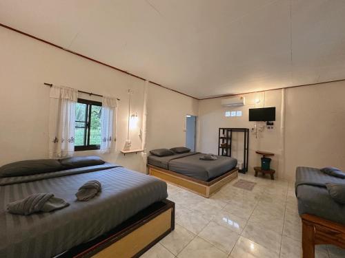 a bedroom with two beds and a tv in it at Khao Sok Jungle Huts Resort in Khao Sok National Park