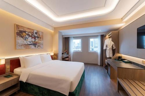 a hotel room with a large bed and a television at NiK Hotel Thi Sach in Ho Chi Minh City