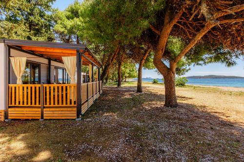 a small house on the beach with a tree at Mobile Homes Camp Perna - Adriatic Kampovi in Orebić