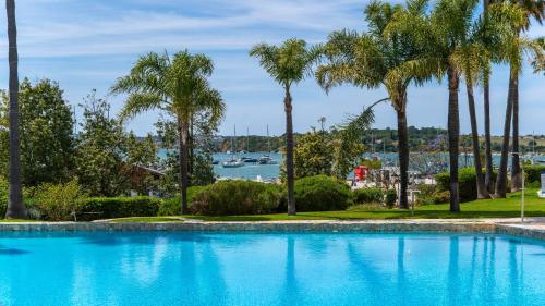 a swimming pool with palm trees and a harbor at Clube Alvor Ria - Prime Residence in Alvor