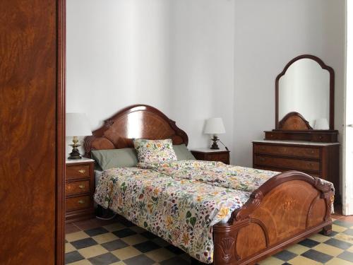 a bedroom with a wooden bed and two dressers and a mirror at Casa l'àvia - Sant Pol de Mar in San Pol de Mar